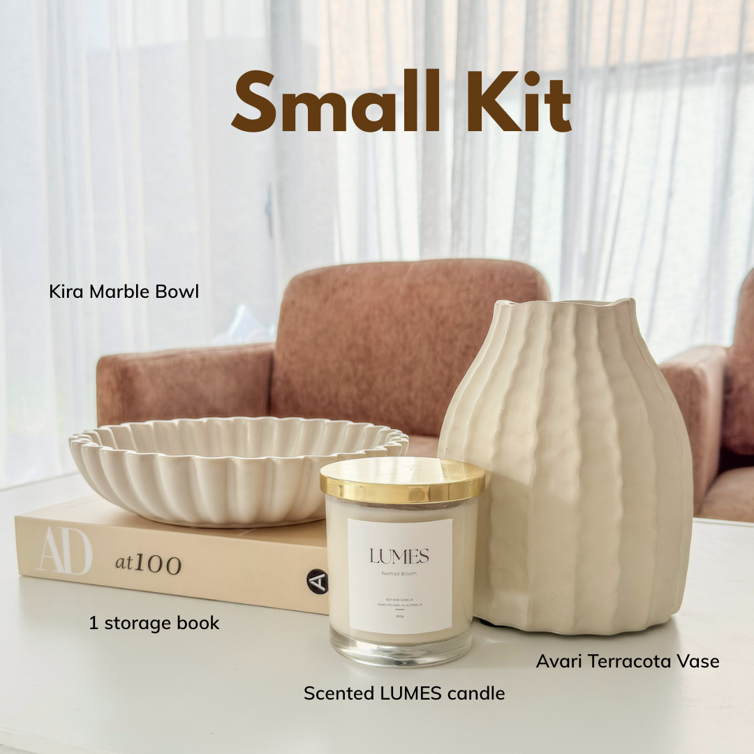 A styled home decor small kit on a white table, featuring a Kira Marble Bowl, a Scented LUMES candle with a gold lid, an Avari Terracotta Vase, and a beige storage book. The image includes text labels identifying each item and the title 'Small Kit' at the top.